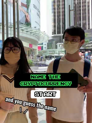 The cover image shows two people, a woman on the left and a man on the right, standing outside in front of a building. Each is wearing a face mask and glasses. Text overlays on the image read 'NAME THE CRYPTOCURRENCY' and 'START' with additional text below. The background features a blurred outdoor scene with buildings and signs.