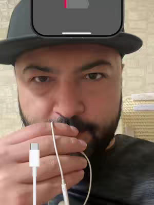 The cover image features a man with a beard and a hat, seen from the chest up. He's holding a pair of white earbuds to his mouth, while a charging cable with the type-c connector dangles below, suggesting an active video session. Above his head is the image of an iPhone with a low battery and black screen.