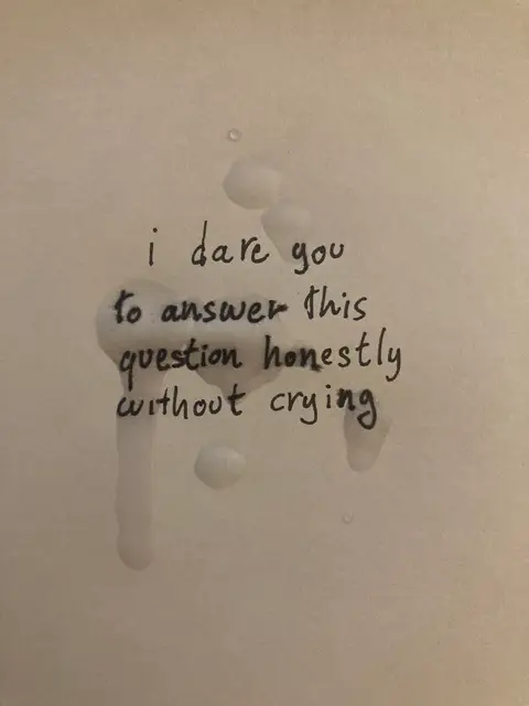 The cover image displays handwriting on a lightly textured white surface. The text, in black marker, is centered and includes a question framed as a challenge, with liquid blotches subtly altering the word forms. The image has a minimalist aesthetic, focusing on the handwritten message and the visual texture created by the wet spots.