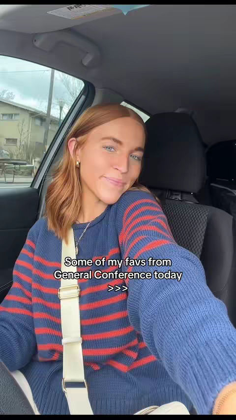 A woman with auburn hair and fair skin is shown from the chest up, smiling slightly. She's in a vehicle; the interior and seatbelt are visible. Text overlay is visible.