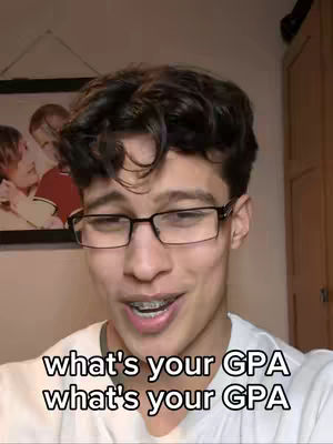 A young man with dark curly hair and glasses looks directly at the camera, smiling slightly. The background is a room with a framed picture on the wall. Text overlays at the bottom reads "what's your GPA" twice.
