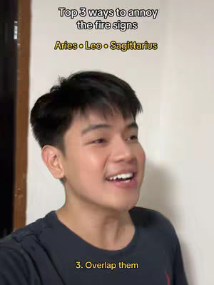 A young man is centered in the frame, smiling and looking towards the side, likely mid-sentence. Above him, text indicates the video's topic, with the phrase "Top 3 ways to annoy the fire signs" and the zodiac signs Aries, Leo, and Sagittarius listed below it.