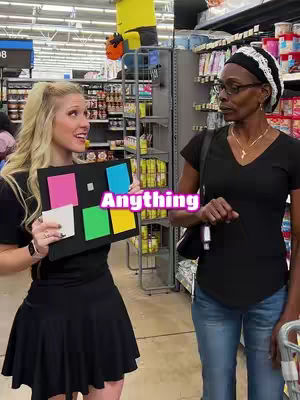A woman in a black dress holds a board with colored squares in a Walmart store. Another woman stands nearby, looking at the board. The image is brightly lit and has a casual, candid feel.