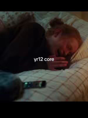 A person is lying on a bed, their face is contorted in what appears to be a sob or a deep laugh, the image has a moody, slightly dark tone. The text overlayed on the image says 'yr12 core'.