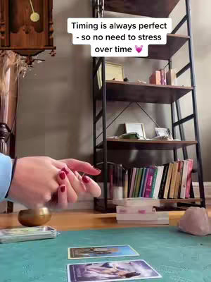The cover image shows a woman's hands, with red nail polish, in front of a teal table. On the table are tarot cards and a golden bowl. In the background is a bookshelf and a wall clock. The text overlay suggests the content is about timing and stress.