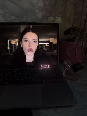 A laptop screen displaying a person wearing a black top, eyes and lips are visible, with the word "you" overlaid at the bottom.