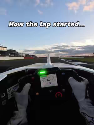 View from inside a race car cockpit, looking forward down a racetrack. A text overlay reads, "How the lap started..."