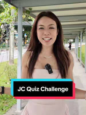 A woman smiles directly at the camera while standing in an outdoor walkway. A colorful text box overlays her torso, and a microphone is clipped to her dress. The background includes foliage and a covered walkway.