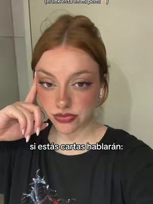 The image showcases a young woman in a close-up shot, with her face filling the frame. She has fair skin, red hair, and strong makeup. Above the text, there is a text overlay saying "(el link está en mi perfil) ." The hook is written in the text.