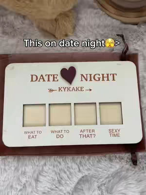 The cover image shows a white wooden board with spaces for different categories and a brown border. The header says "DATE NIGHT," with a heart symbol. Below, there are four boxes labeled "WHAT TO EAT," "WHAT TO DO," "AFTER THAT?" and "SEXY TIME," respectively. The background has some fabric in a neutral color.