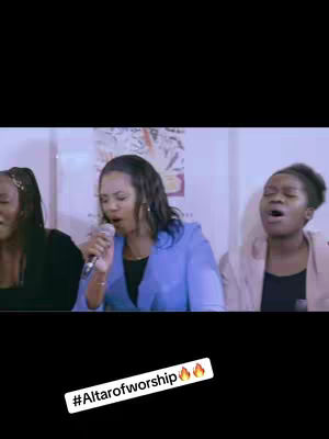 Three women singing and worshiping, a microphone in view in the middle of them. The text overlay has the hashtag of the event.
