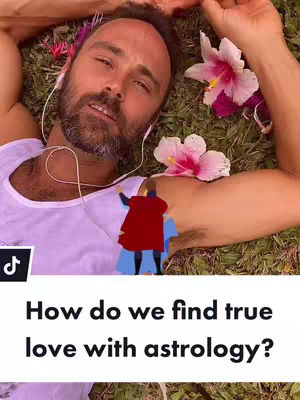 A man lies on a grassy surface with his arms raised and a serene expression. He has a beard and is wearing a white tank top, with earphones in his ears. Above his body is an illustration of a person wearing a red cape and blue pants. The background has green grass and pink flowers.