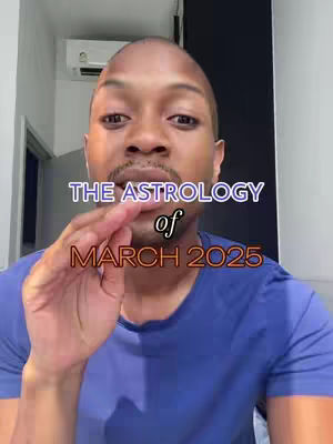 A man with a shaved head and a blue shirt appears close to the camera. Text overlays read "THE ASTROLOGY" in a white and blue gradient font over a darkened space. The word "of" is centered underneath, and "MARCH 2025" in a darker, red-orange gradient font fills the image. The man is gesturing as if speaking.