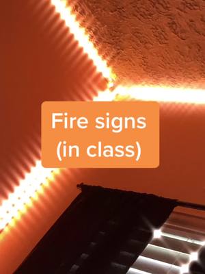 An image shows a close-up view of an orange-lit ceiling corner. The light emits from a linear source. There's a rectangular orange box in the middle with white text. The corner of a dark object is also in the shot.