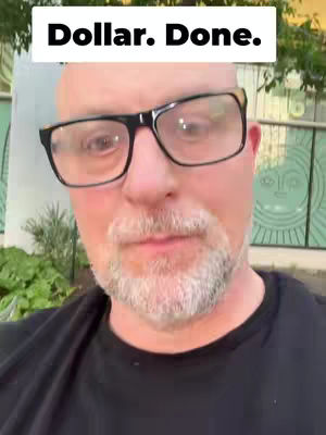 A close-up shot of a man wearing glasses. He has a shaved head and a trimmed grey beard. Above his head is a white rectangle with the text 'Dollar. Done.' written in bold, black font.