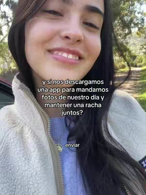 A young woman with dark hair and a white sherpa jacket smiles directly at the viewer, set against a blurred outdoor background. Overlay text in white describes an app to share photos and maintain a streak. The overall composition is warm and inviting, with a natural, casual feel.