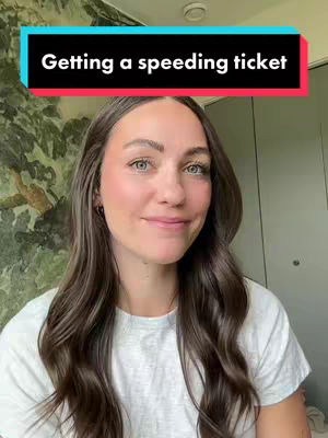 A woman with long brown hair smiles at the camera. She wears a white t-shirt and has natural-looking makeup on. A text overlay in a colorful box reads, "Getting a speeding ticket". The background is a muted floral pattern.