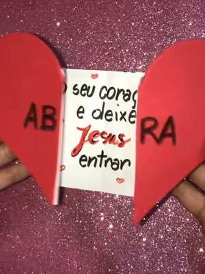 The image shows a split-heart design with a white card in the middle. The background is a glittery pink surface. Each half of the heart contains a single letter; they read "AB" and "RA" respectively. The rest of the central card is filled with text, "seu corag e deixe Jesus entrar", and a heart symbol below. The overall composition is centered, highlighting the message of Jesus.