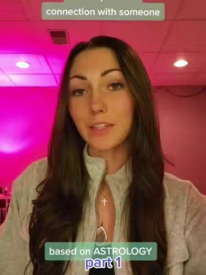 A woman with long dark hair stands in front of a pink-lit backdrop. The image is a medium shot, with the woman's face centered. She wears a light, collared shirt and a necklace with a cross and a teardrop-shaped pendant. Text overlays provide context and branding.
