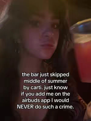 A medium shot features a person, likely the content creator, against a dimly lit bar setting. They have dark hair and are looking at the camera with a slightly pensive expression. The person is holding a glass of red liquid, presumably a drink, in their right hand, partially obscuring the view. Text is overlaid on the image, offering context or a message.