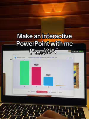A laptop is open on a table, displaying a PowerPoint presentation with a bar graph. The screen shows options A, B, C, and D, with the bars in green, red, blue, and yellow respectively. At the top, text says 'Make an interactive PowerPoint with me,' and the screen is lit by a warm light from above. The laptop keyboard and a hand are visible in the frame.