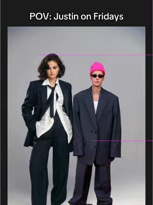 Two people in oversized suits stand side by side against a gray background. One person is wearing a pink beanie and sunglasses, while the other is wearing a white top and a black tie.
