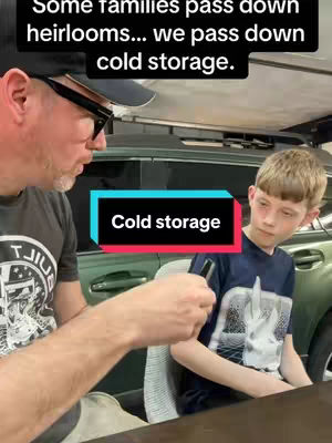 A man and a young boy are in a car setting. The man is holding a small black item, potentially a device or hardware wallet, and is talking to the boy. Both are looking at the device. The image combines text overlay elements with real-life environment.