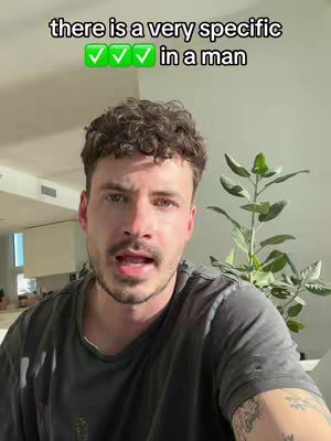 A man with short dark hair and a beard is looking at the camera. The text overlay reads 'there is a very specific ✅✅✅ in a man.' Behind him is a mostly out-of-focus background with a plant.