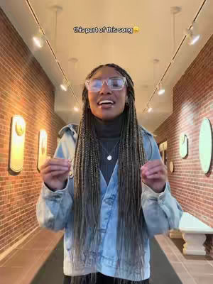The cover image shows a woman with long braided hair, wearing glasses and a denim jacket, standing in a hallway. The hallway has brick walls and is lit by overhead lights. Text overlayed says 'this part of this song'.