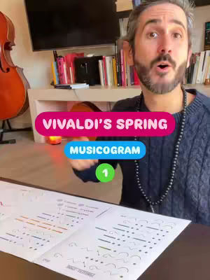 A man with short, gray hair and a beard stands in front of a camera with books, a cello, and a TV in the background. Text overlays say, "VIVALDI'S SPRING" in a pink bubble and "MUSICOGRAM" in a blue bubble.