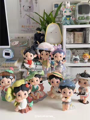 The cover image displays a collection of small collectible figurines, arranged on a white shelf against a backdrop of other objects. The figurines are the primary focus, each uniquely designed and painted with vibrant colors. They are positioned closely together, filling the majority of the frame. Behind them, the shelf is lined with various items, including a computer monitor, a plant, and some other collectibles that create a sense of a lively and personal space. The color palette is bright and varied, with the figurines standing out due to their detail and design. The overall composition suggests a focus on the figurines as the primary subject of this video.