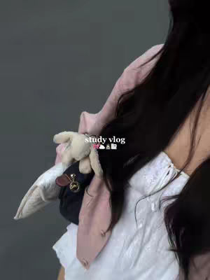 A person's profile is shown. The image is dark and blurry, focusing on a person's shoulder and hair. A small purse with a doll is placed on the shoulder. The hook 'study vlog' is added.