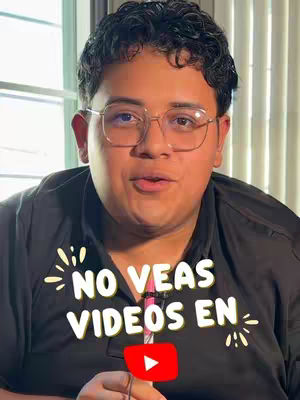 A medium shot shows a young man with dark curly hair, wearing glasses and a dark top, looking directly at the camera. He has a slight smile. Overlaid on the image is text in a casual font with a YouTube logo incorporated. The background gives a sense of indoor lighting with a window visible.