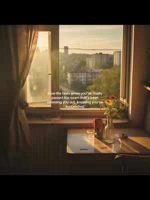 A window with a view of a cityscape is shown. Inside, a table holds a bottle of flowers, a mug, a glass, and other items. The lighting is warm from the sun filtering through the window.