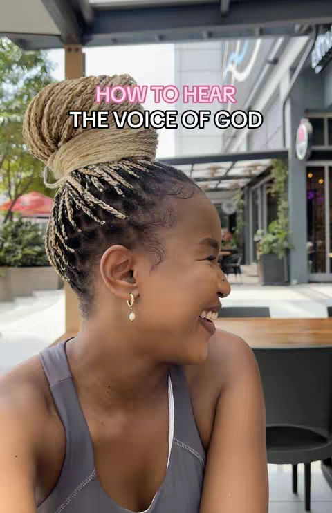 A woman with braided hair is smiling, with text overlayed on the top of the image. The background shows an outdoor cafe setting with greenery.