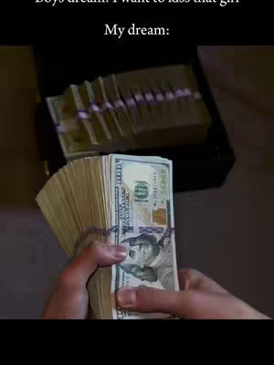 The image shows a person holding a stack of US dollar bills. Behind the money, there is a briefcase filled with more stacks of money. The top of the image contains text which indicates the text on the image is a person's dream.