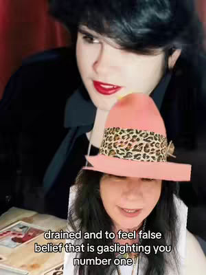 The cover image shows two women. The foreground person dons a hat, the upper one has dark hair and red lip. The background person wears a black top. In the bottom are the words: drained and to feel false belief that is gaslighting you number one