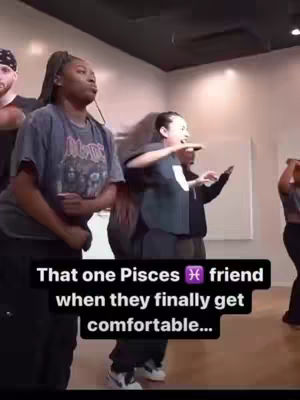 A group of people are in a dance studio with one person in the foreground. The people are dancing and moving, and a text overlay is added to the image.