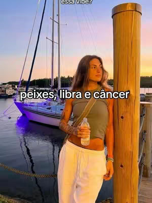 A woman in casual clothing stands beside a wooden pillar with a boat and water in the background. Text overlays read "peixes, libra e câncer."