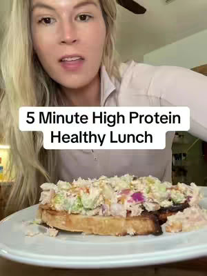 A woman is holding a plate with a healthy lunch containing tuna salad on top of a bread. Text overlay says "5 Minute High Protein Healthy Lunch."