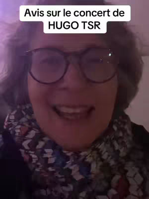 A smiling older woman with glasses is the main subject, set against a blurry background. She is wearing a patterned scarf. Above her is a text overlay.