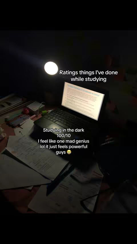 A top-down view of a dimly lit desk, centered around a laptop with a glowing screen. Scattered papers and items surround the laptop, suggesting a workspace, with the lightbulb in the background. Text overlays provide context.