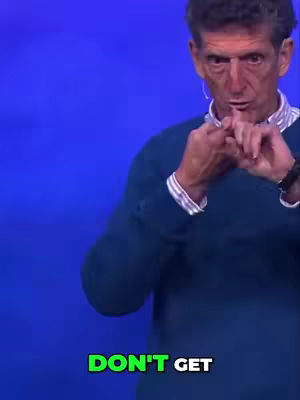 The image shows a man with short hair wearing a blue sweater. He is holding his hands up, with his figures interlocked, against a blue background. At the bottom is a green text overlay.