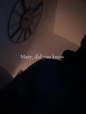 The image presents a dimly lit indoor scene, possibly a room or a hallway, with the primary focus on a large, circular clock near the ceiling. The clock's design is intricate, with radiating lines and numerals. The upper right part has a source of light emanating from a wall, while the foreground shows a silhouette