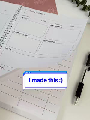The image showcases an open spiral-bound notebook with handwritten notes and diagrams related to academic writing. A blue and white pop-up box overlay reads "I made this :)". A pen lies nearby on a white surface, with a pink patterned notebook in the background, implying a workspace.