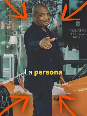 A man in a black suit stands beside an orange sports car, pointing towards the viewer. The background includes a building with the text "ADDRESS SKY VIEW HOTEL". The cover uses a warm color palette of orange, black, and neutral tones.