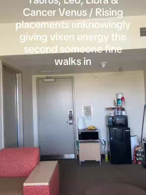 The image shows a room interior, likely an apartment or hotel room, with a view of a door, a couch, and a small kitchenette area. The color scheme is neutral, with a mix of whites, grays, and browns. The layout includes a door, a couch, a small refrigerator, and a microwave on the counter. The text overlay is white, positioned at the top of the frame.