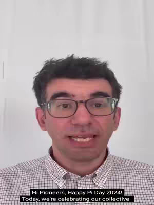 A medium shot shows a man with short, dark hair and glasses, speaking directly to the camera. He's wearing a checkered shirt against a plain white backdrop. Below him, text overlays provide additional context.