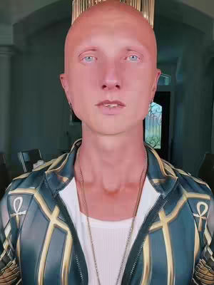 A close-up shot of a man with a shaved head and light blue eyes. He's wearing a white ribbed tank top and a dark jacket with gold accents and an Egyptian hieroglyphic pattern. The background is slightly blurred, but appears to be indoors with a chandelier visible.