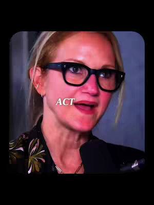 A medium shot focuses on a woman wearing black-framed glasses and a dark-colored blazer with a floral design. The word "ACT" is overlaid, and a microphone is partially visible. The background is dark and blurred.